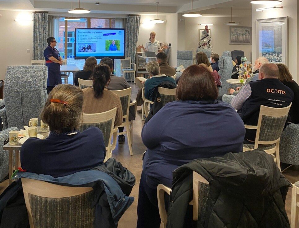 A group of people sit watching a presentation in the hospice's Living Well Centre during a Networking Breakfast event.