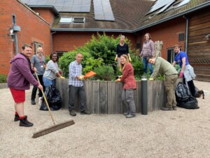 A group of volunteers with gardening equipment working on a raised flower bed