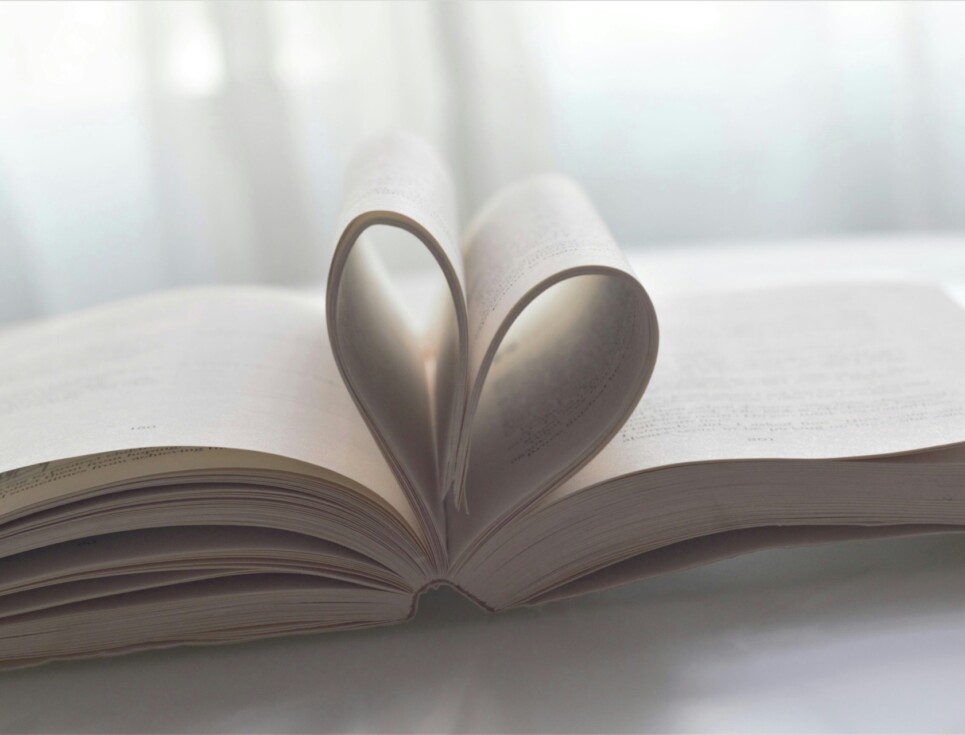 An open book with pages folded to form a heart shape.