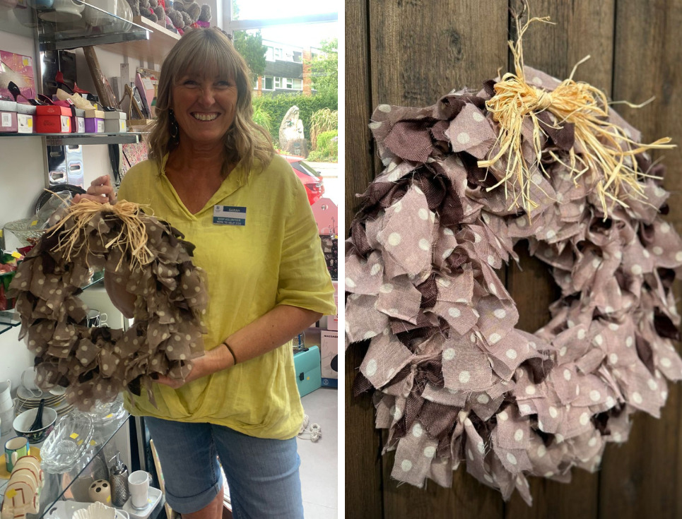 Two images side by side. The left image shows volunteer Sarah stands in a St Richard's shop holding a handmade fabric wreath crafted with pale brown and white polka dotted fabric. Sarah is wearing a bright yellow top and denim shorts. She is smiling. The right hand image is a close-up image of the fabric wreath made from light brown and white polka dot fabric with a straw coloured raffia bow at the top.