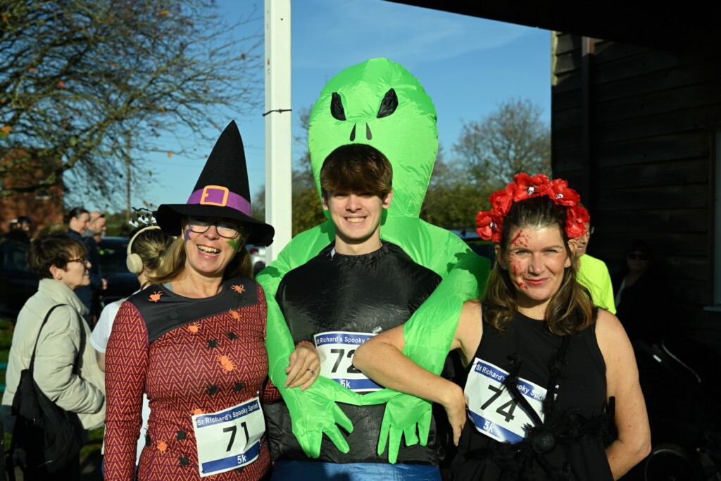 Three people dressed in Halloween costumes at the hospice's Spooky Sprint on a sunny day.