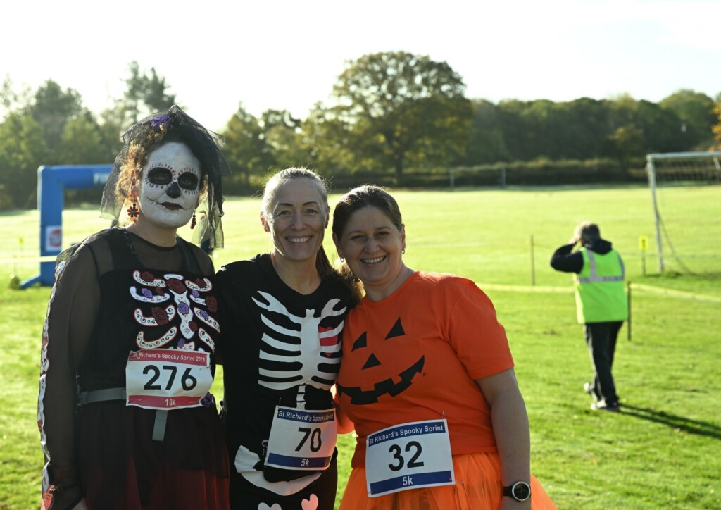 Three people in Halloween costumes at the hospice's Spooky Sprint on a sunny day.