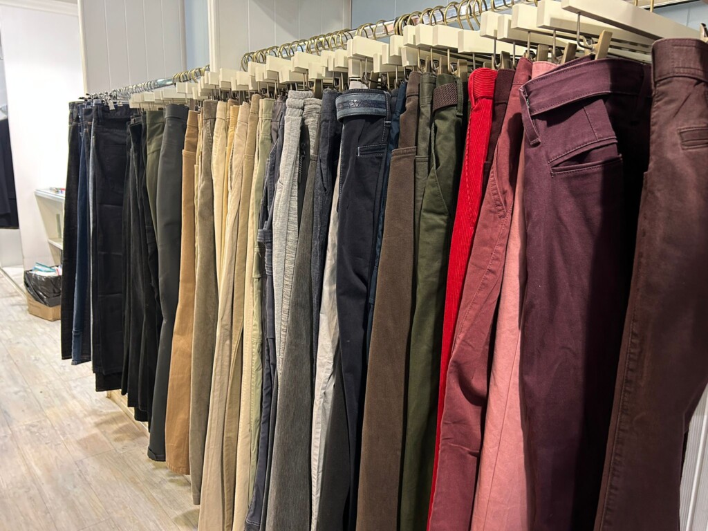 Men's trousers on a rail in the hospice's pop-up shop. 