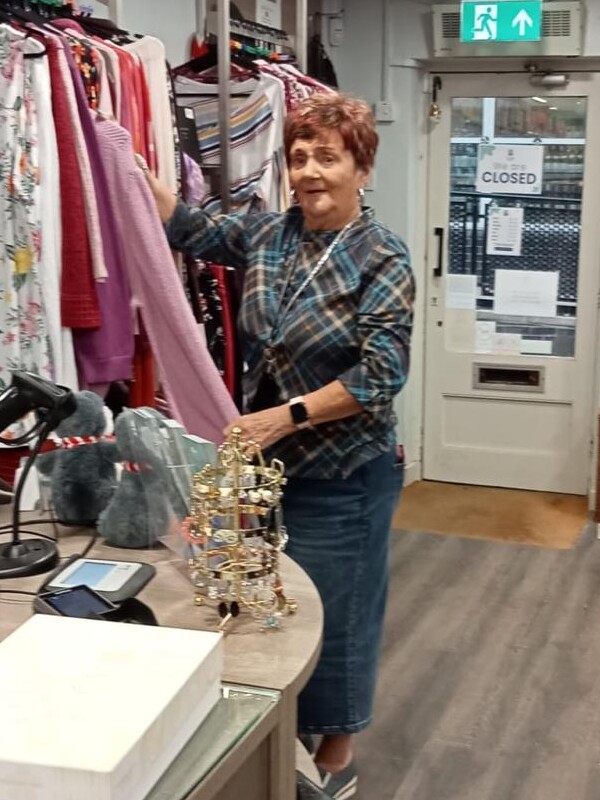 Sylvia arranges a rail of clothing in a hospice shop.