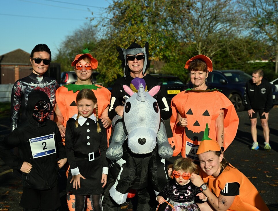 A group of adults and children dressed in a range of Halloween fancy dress outfits stand together at the hospice's Spooky Sprint run.